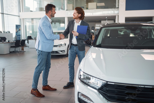 Buyer shaking hand with salesman in car sales salon