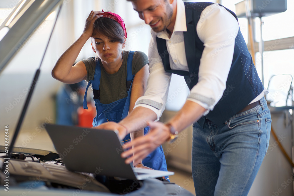 Worried woman with man in workshop looking at a laptop Worried woman with man in workshop looking at a laptop