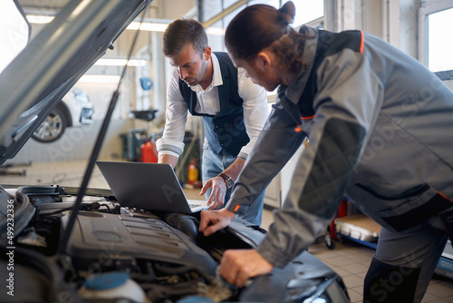 Two men in auto service repairing a car