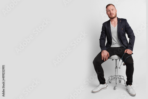 Doctor sentado en un fondo blanco atajando el estetoscopio  photo