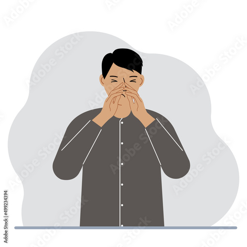 The man covers his nose with his hands. The concept of a sick person, sneezes, seasonal allergies, bad smell.
