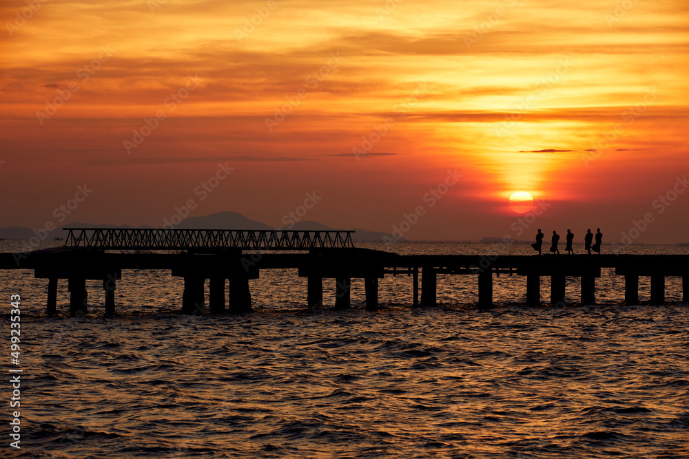 Monk walk on the bridge at sunset in evening near the beach.