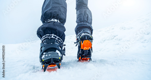Winter mountain ascending in boot crampons by tourist