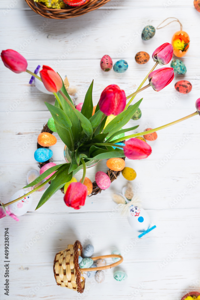 easter colorful eggs with tulips and spring flowers on a white wooden background