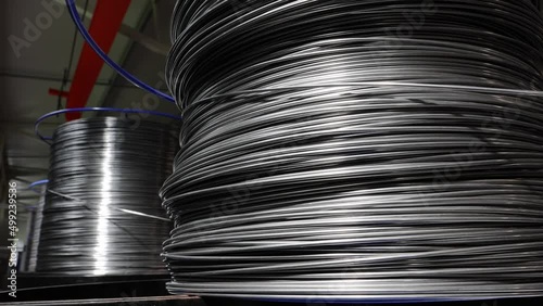 The process of slow unwinding of a metal wire used for a production of metal baskets in an industrial hall.