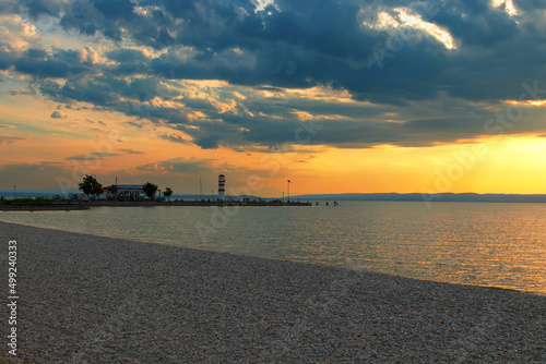 Road leading to the lighthouse in the town of Podersdorf on Lake Neusiedl in Austria. In the background is a dramatic sunset sky