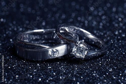 Two diamond ring on black glitter background.