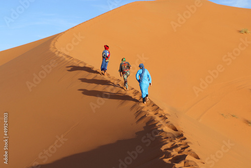 People walking on dune of sand in Sahara desert in Africa