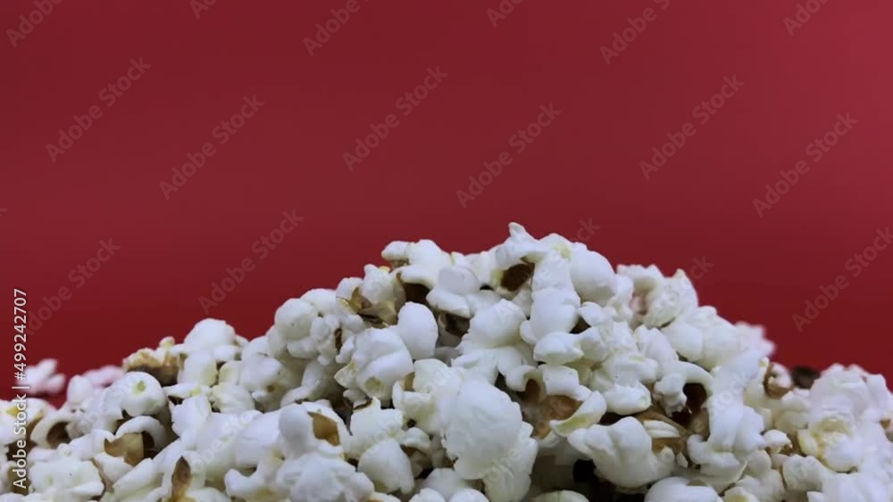 Falling popcorn in slow motion on a red background.