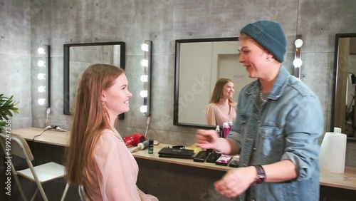 make-up artist applies powder on neck of red-haired girl