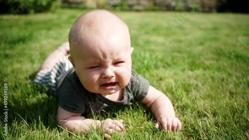 baby lies on grass and begins to cry slow motion