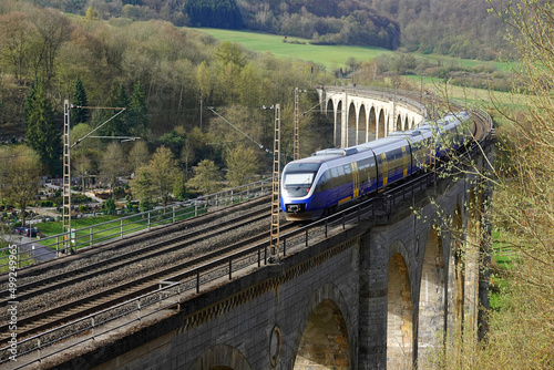 A train is speeding over an old railway viaduct. It is a 482 metres long and up to 35 metres high and made out of limestone in 1853. It spans a valley west of the town of Altenbeken.