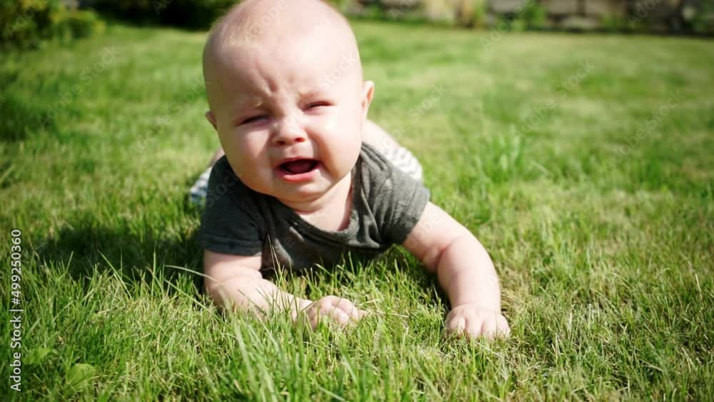 two-month-old baby lies on lawn and cries two-month-old baby lies on lawn and cries