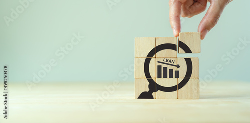 Lean manufacturing management. Cost reduction concept. Process improvement. Maximising productivity and quality, reducing time and cost. Wooden cubes with LEAN text, decreasing graph and magnifier.