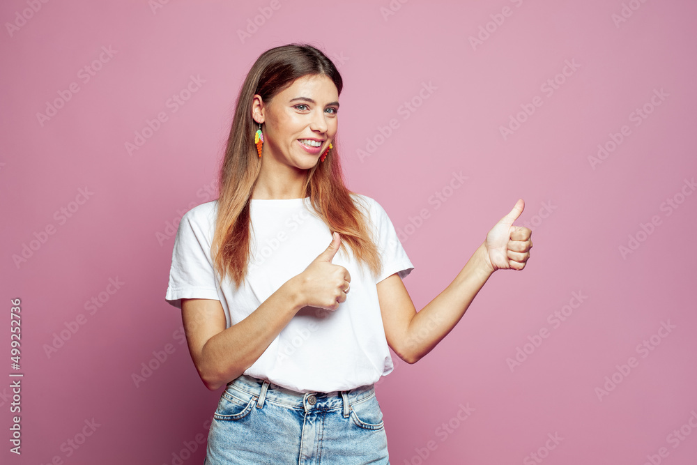Cheerful hipster woman in white t-shirt making thumb up gesture and smiling joyfully, showing her support and respect to someone. Good job, Well done, I like that concept Cheerful hipster woman in white t-shirt making thumb up gesture and smiling joyfully, showing her support and respect to someone. Good job, Well done, I like that concept