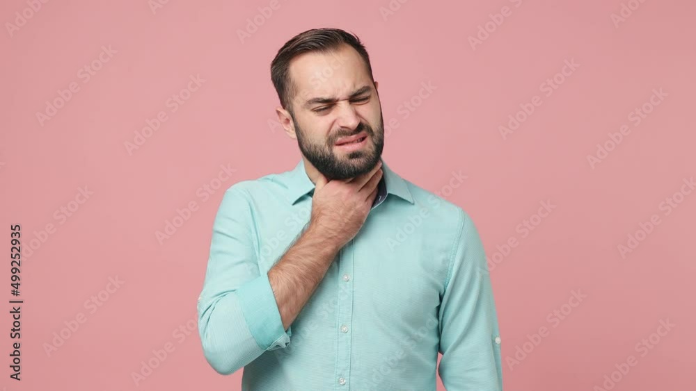 Sick ill tired young brunet man 20s wears blue shirt feel bad seedy has sore throat touch neck isolated on plain plain pink background studio. Healthy lifestyle disease treatment cold season concept Sick ill tired young brunet man 20s wears blue shirt feel bad seedy has sore throat touch neck isolated on plain plain pink background studio. Healthy lifestyle disease treatment cold season concept