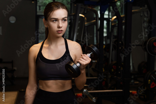 Beautiful athletic fitness young woman workout with dumbbells in fitness gym.