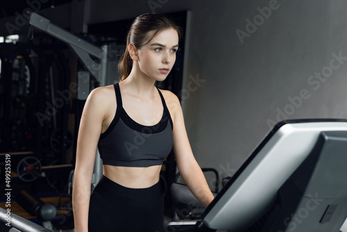 Attractive sports woman is working out in gym. Doing cardio training on treadmill.