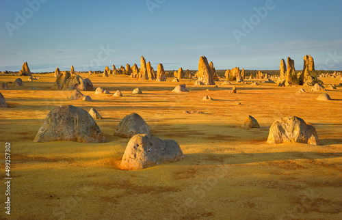 Sunrise over a desert landscape with weathered limestone pillars and boulders, Pinnacles Desert, Western Australia