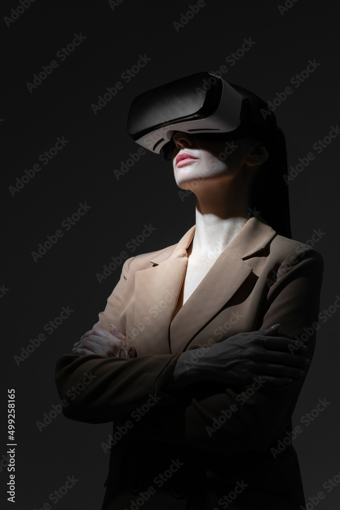 Serious business woman in virtual reality glasses is watching the working process. Modern leader. She folded her hands.