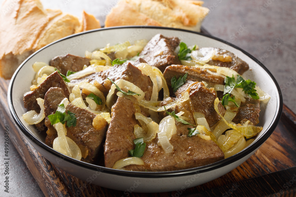 Grilled Liver with Onions closeup in the bowl served with bread on the table. Horizontal Grilled Liver with Onions closeup in the bowl served with bread on the table. Horizontal