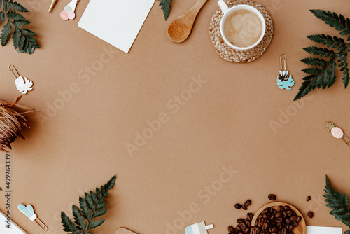 Top view brown neutral workspace office desk with coffee and office supplies. Flat lay work table with craft notebook, green olive leaf and supplies. Home blogger photo