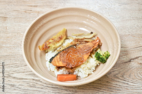 grilled salmon soy sauce with pork dumpling and vegetable topping on Japanese rice in bowl