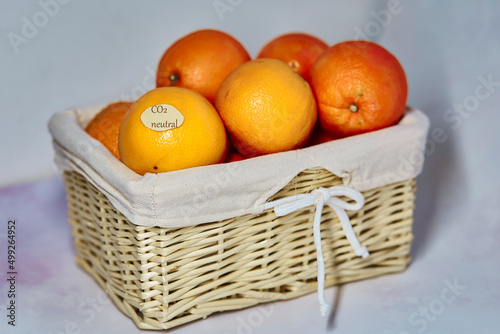 CO2 neutral label on oranges in wicker basket. Carbon labeling. Net zero carbon, emissions free. Organic farm products from local market close up.