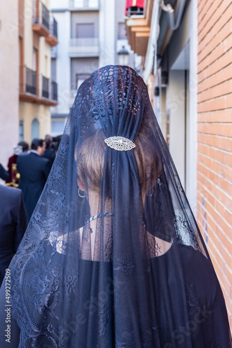 Detail of the head of a woman with a black spanish mantilla and peineta (ornamental comb), seen from behind, in a Holy Week procession photo