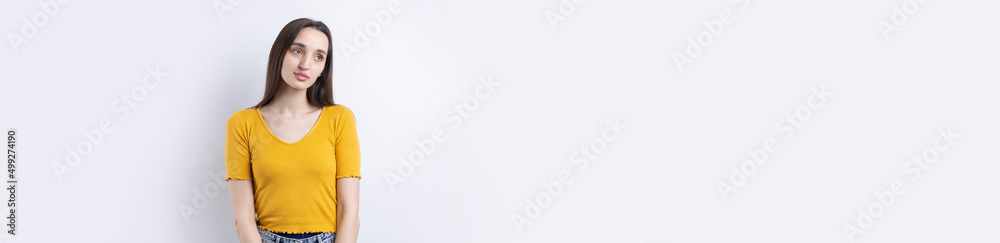 Fototapeta premium Portrait of a beautiful young woman thinking, isolated on concrete background