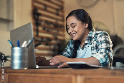 When youre happy, life is easy. Shot of a young woman using a laptop at work.
