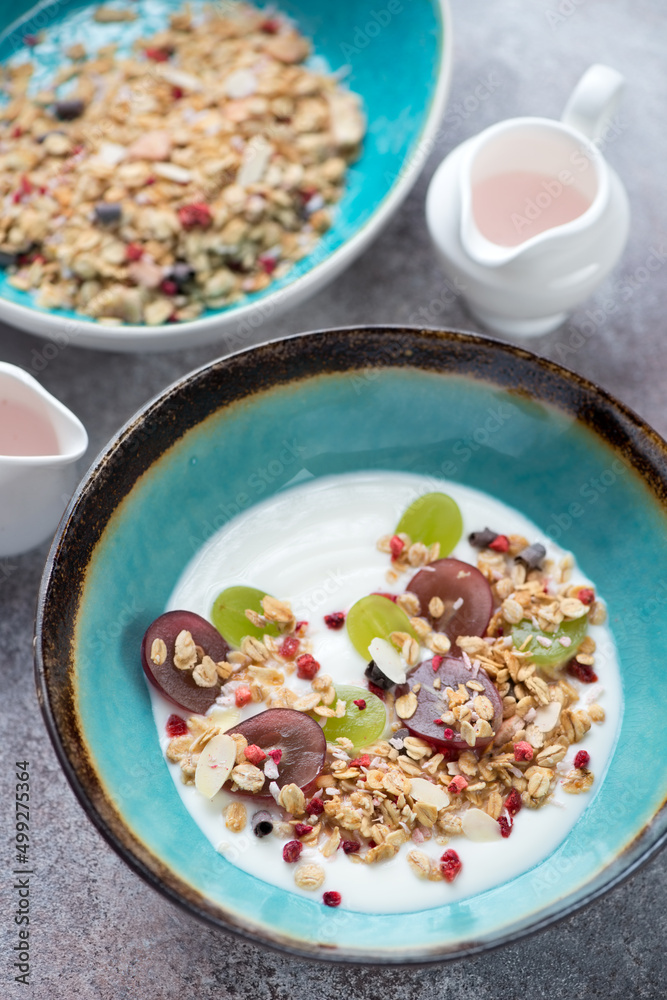 Turquoise bowls with greek yogurt, granola and grapes, vertical shot on a roseate metal surface Turquoise bowls with greek yogurt, granola and grapes, vertical shot on a roseate metal surface