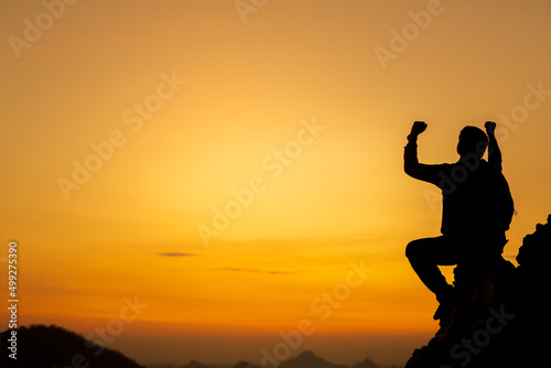 Silhouette of success man hiker outstretched arms on top of the mountain with beautiful sunset. Concept of traveling and hiking adventures