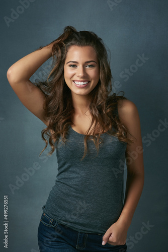 Messy hair dont care. Studio shot of a beautiful young woman posing against a blue background.