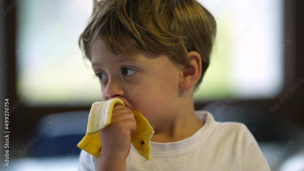 One little boy eating banana child eats healthy snack fruit