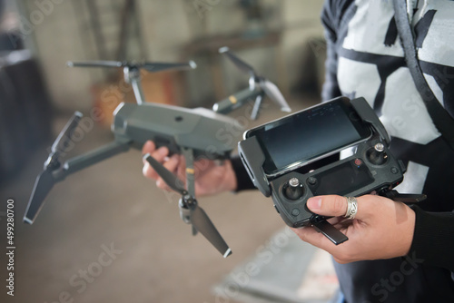 Man holding transmitter with attached mobile device and drone