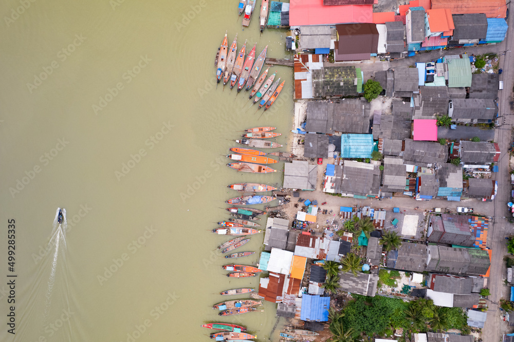 Aerial view top view of the fisherman village with fishing boats and house roof at the pier in suratthani Thailand. high angle view