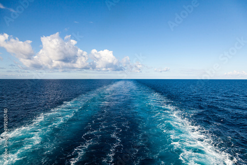 Fototapeta Naklejka Na Ścianę i Meble -  The trail from the movement of the ship in the sea stretching into the horizon with a clear sky with clouds.