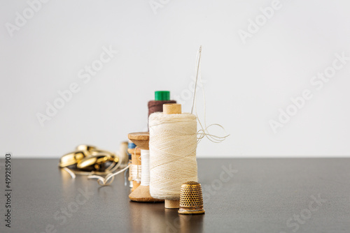 Spools of thread, needle, golden buttons and thimble photo