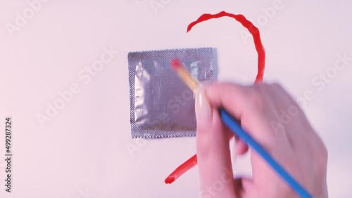 Drawing a heart around a condom in a silver package on a white background. The concept of safe sex, birth control, prevention of AIDS and STDs.
