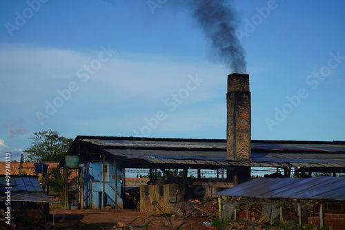 Old factory chimney of a brickyard in the Amazon region of Brazil. The circular kiln is operated with tropical wood and all materials that burn. The smoke is black and pollutes the air. Manaus, Brazil