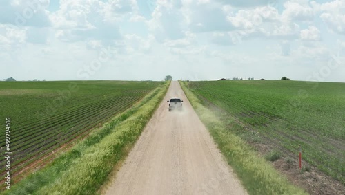Aerial, pickup truck driving on unpaved rural farmland countryside dirt road on summer day.  photo