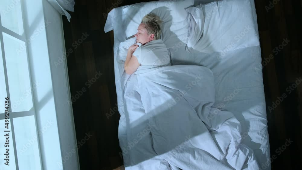 Top view of sleeping woman moves in  dream changing positions in bed in room, person tossing and turning during sleep, time lapse.