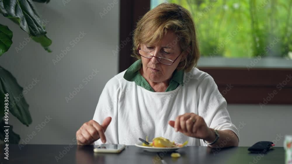 An older woman using technology and eating 70s person browsing internet An older woman using technology and eating 70s person browsing internet