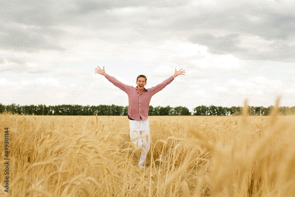 Young happy man with outstretched arms in a wheat field. Concept of freedom Young happy man with outstretched arms in a wheat field. Concept of freedom
