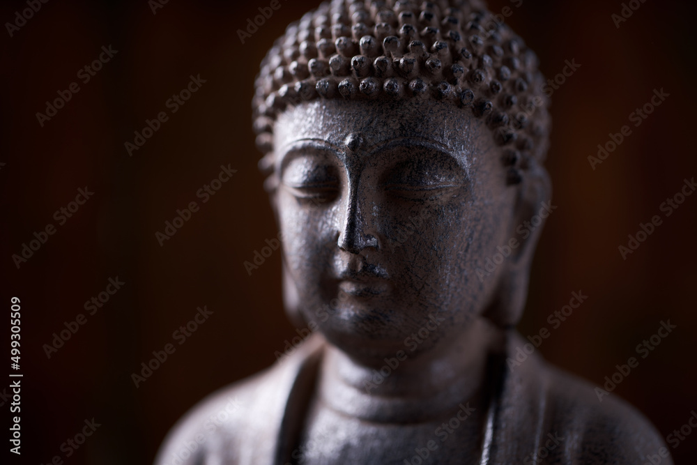 Meditating Buddha Statue on dark wooden background. Close up. Copy space.	