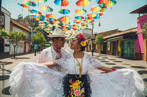 Dancers of typical Mexican dances from the region of Veracruz, Mexico, doing their performance in the street adorned with colored umbrellas. photo