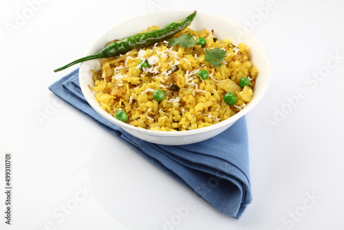 Kande Pohay OR Aloo Pohe is a popular Indian breakfast recipe made using Flattened rice, usually served with hot tea. Served in a bowl over moody background. Selective focus