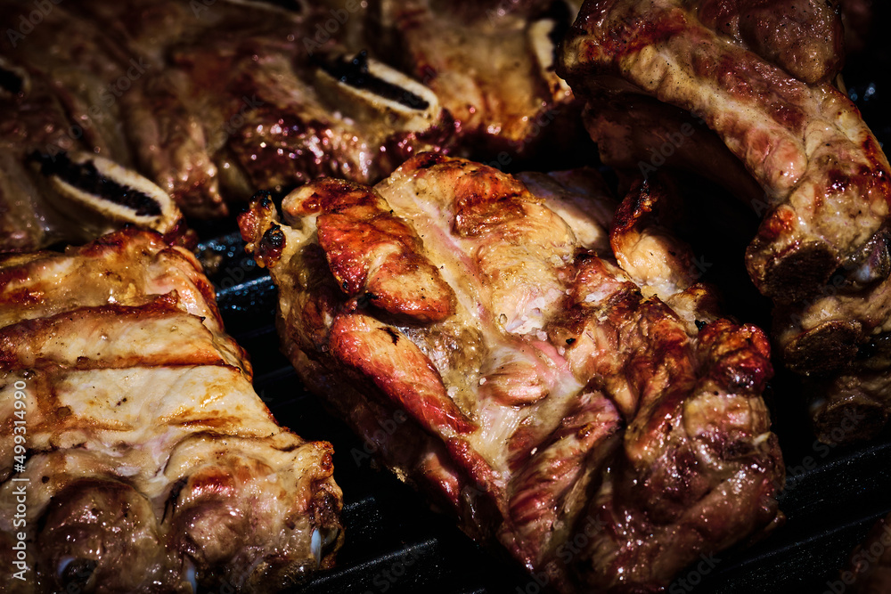 juicy beef rib and pork rib slowly being made on the grill on the fire at a gas barbecue juicy beef rib and pork rib slowly being made on the grill on the fire at a gas barbecue