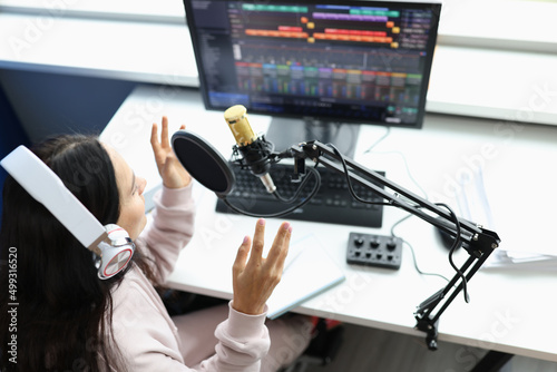 Woman in headphones in front of microphone broadcasts radio